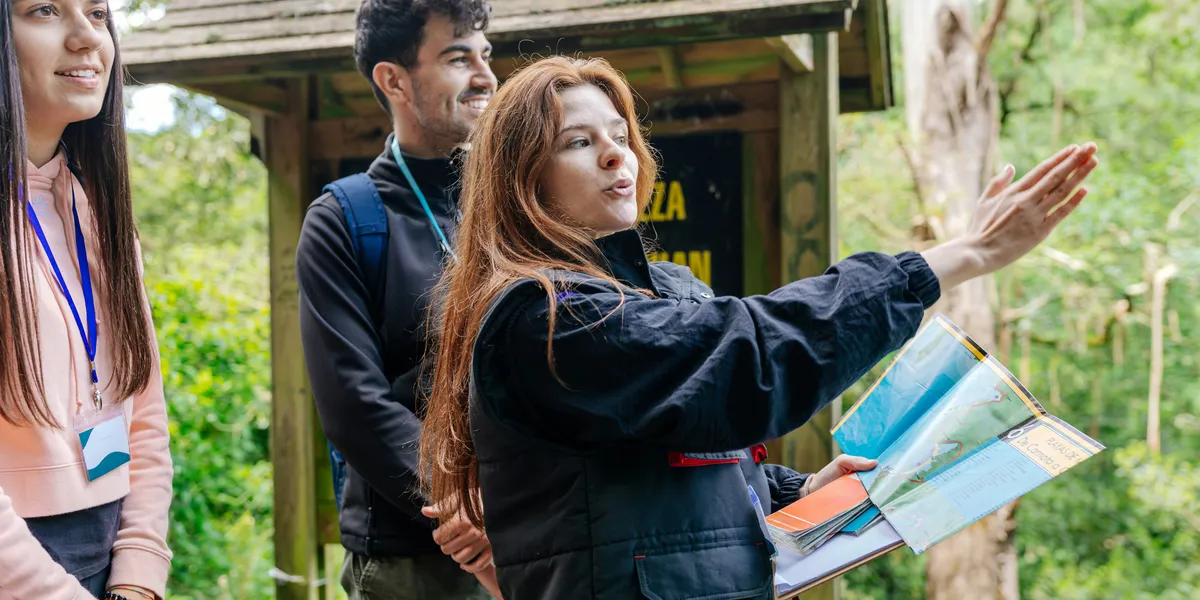 A tour guide holding a map points out the way to a small group of travellers