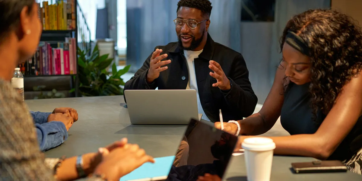 An agency team talking around a table with laptops and coffee