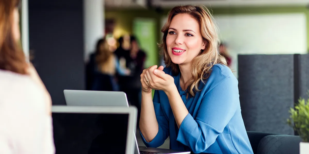 A consultant talking with a colleague across their laptops in a bright office