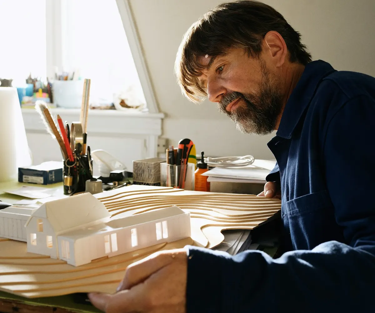 An architect working on a building model at his desk